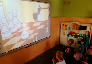 Dzieci oglądają film edukacyjny dotyczący gry w szachy